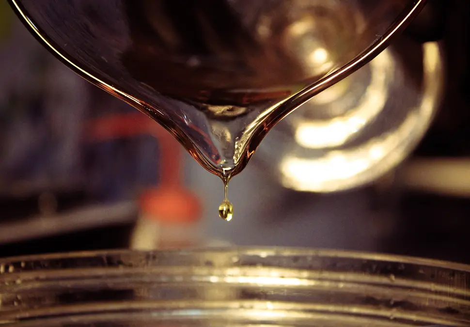 Pouring cologne ingredients from a jar into a large bottle