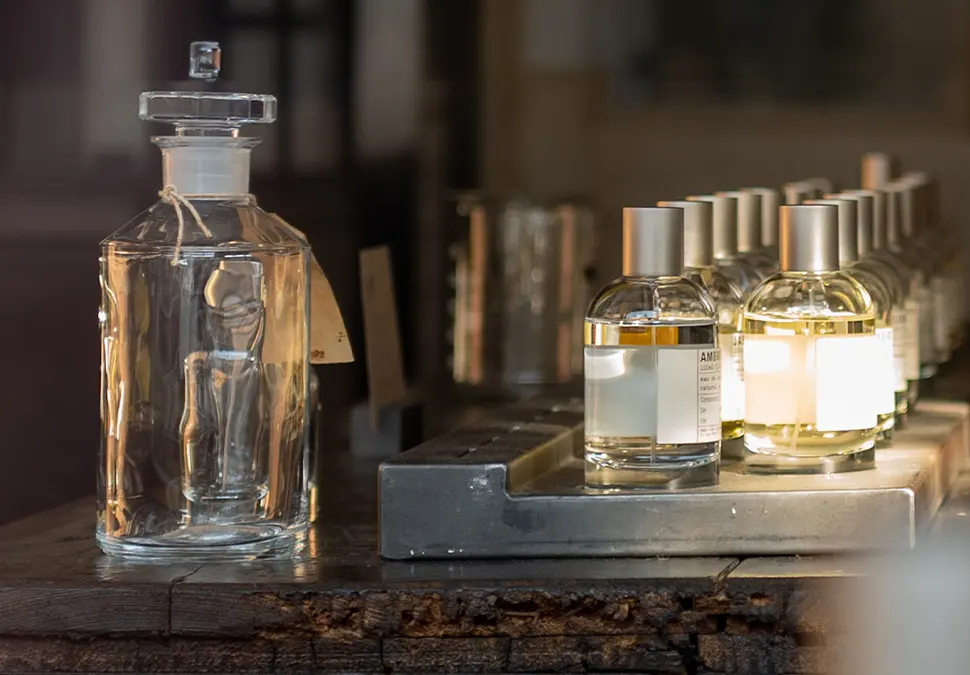 A variety of glass cologne bottles next to a larger glass bottle