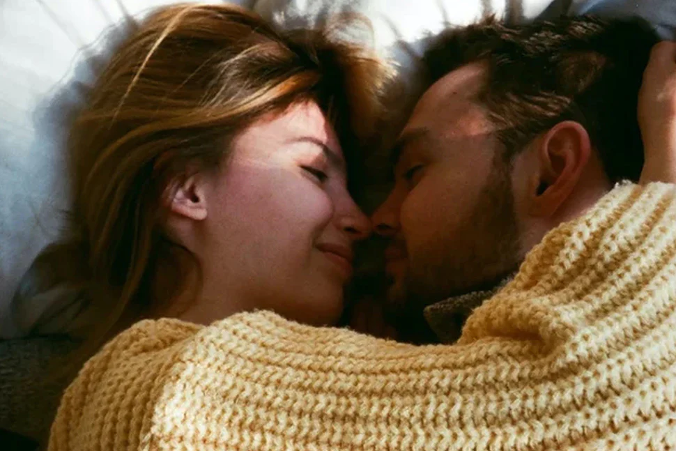 Man and woman in bed smiling and resting against one another