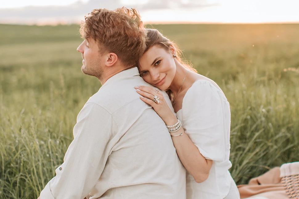 a man looking off into the distance as a woman rests her head on his shoulder and looks into the camera