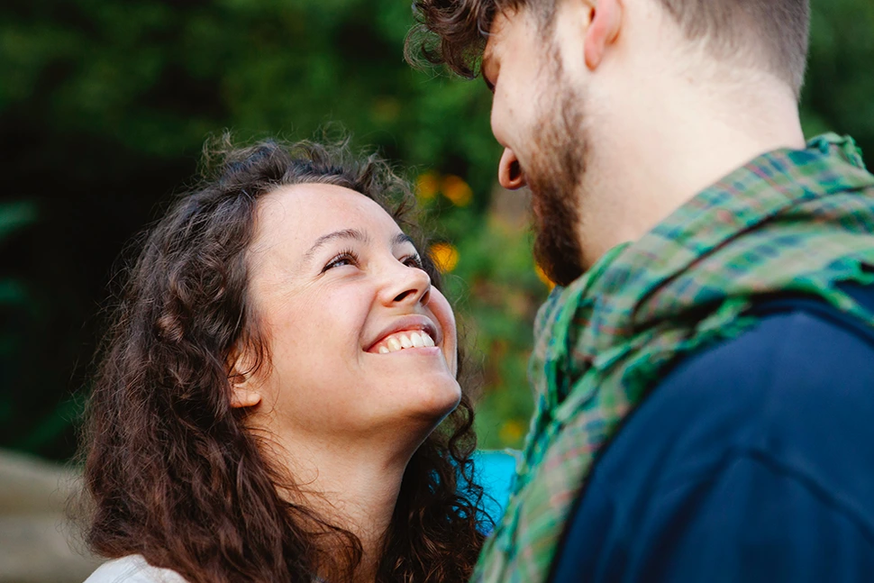 Woman looking up at a man smiling as he looks down on her and smiles back