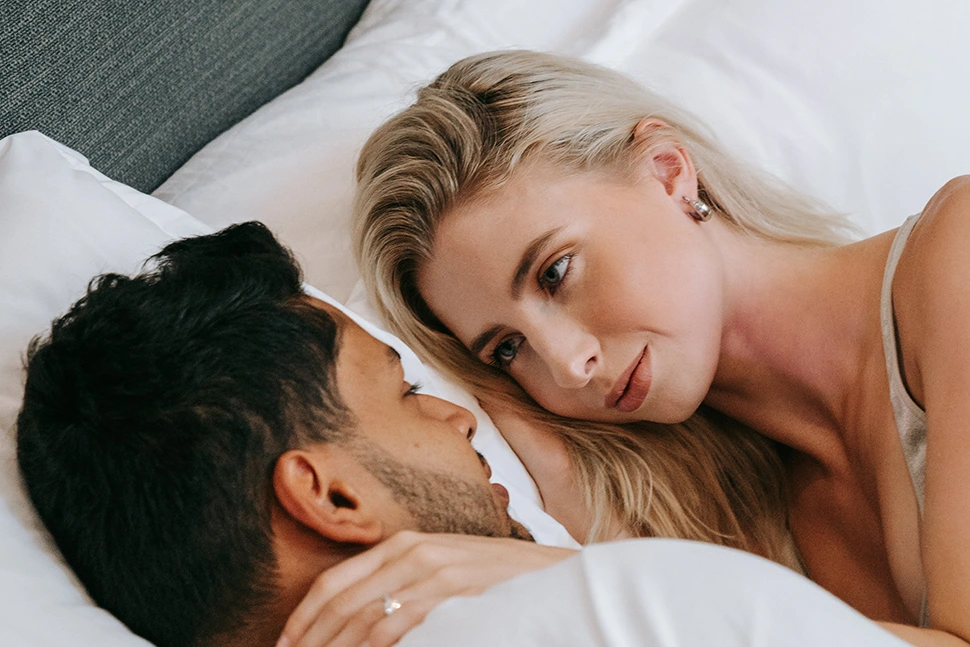 Women looking intently into a mans eyes, they are in bed together