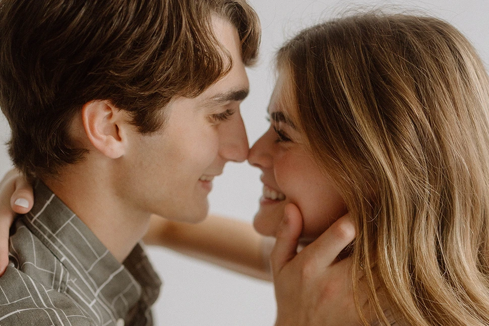 Man and woman smiling at each other, he is holding her face with his right hand