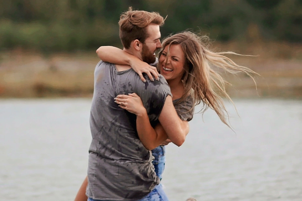 Man and woman playing in a lake together and hugging