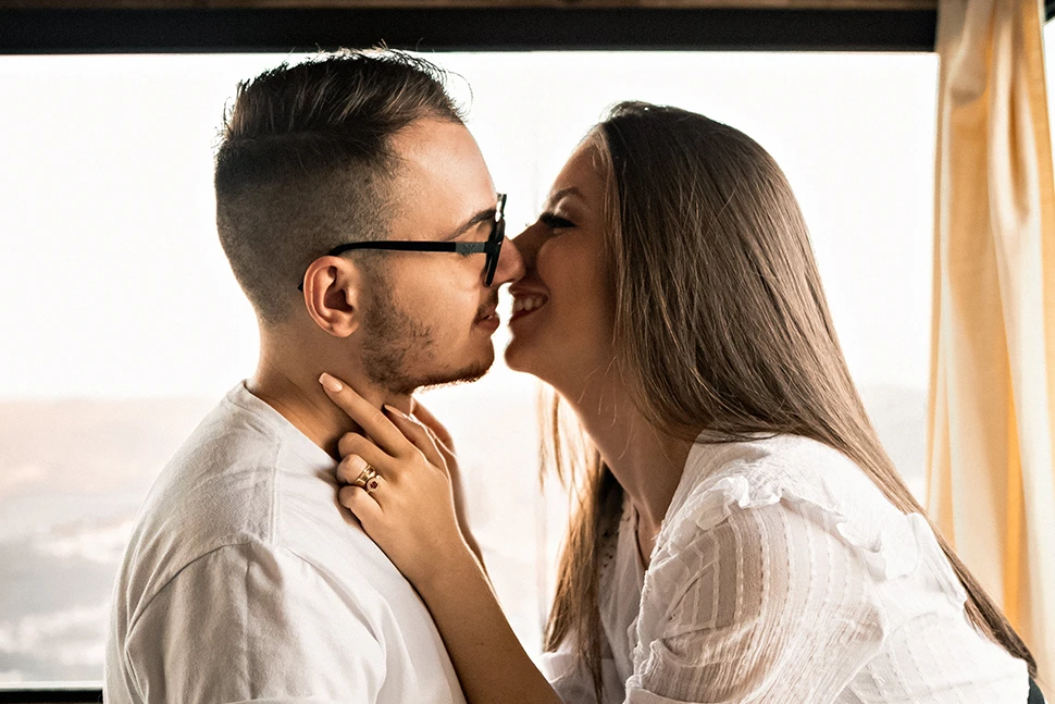 Woman leaning in to kiss a man with glasses on